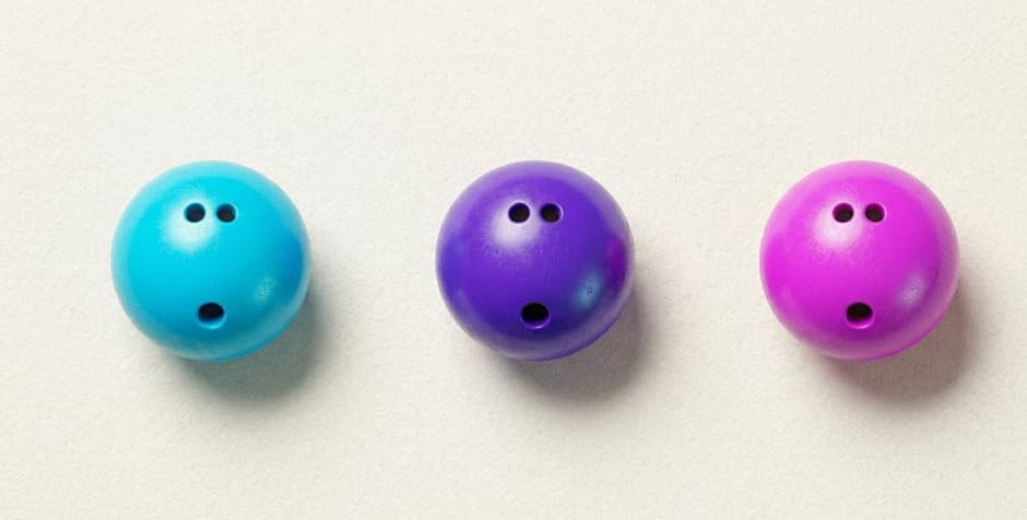 Trois boules de bowling cyan violet magenta vue zénithale flat lay éditorial sur fond crème-bleuté — Le 300