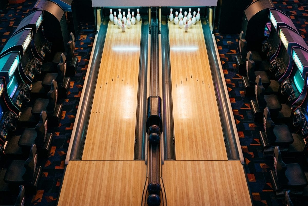 Vue de dessus de deux pistes de bowling courtes entourées de bornes d'arcade